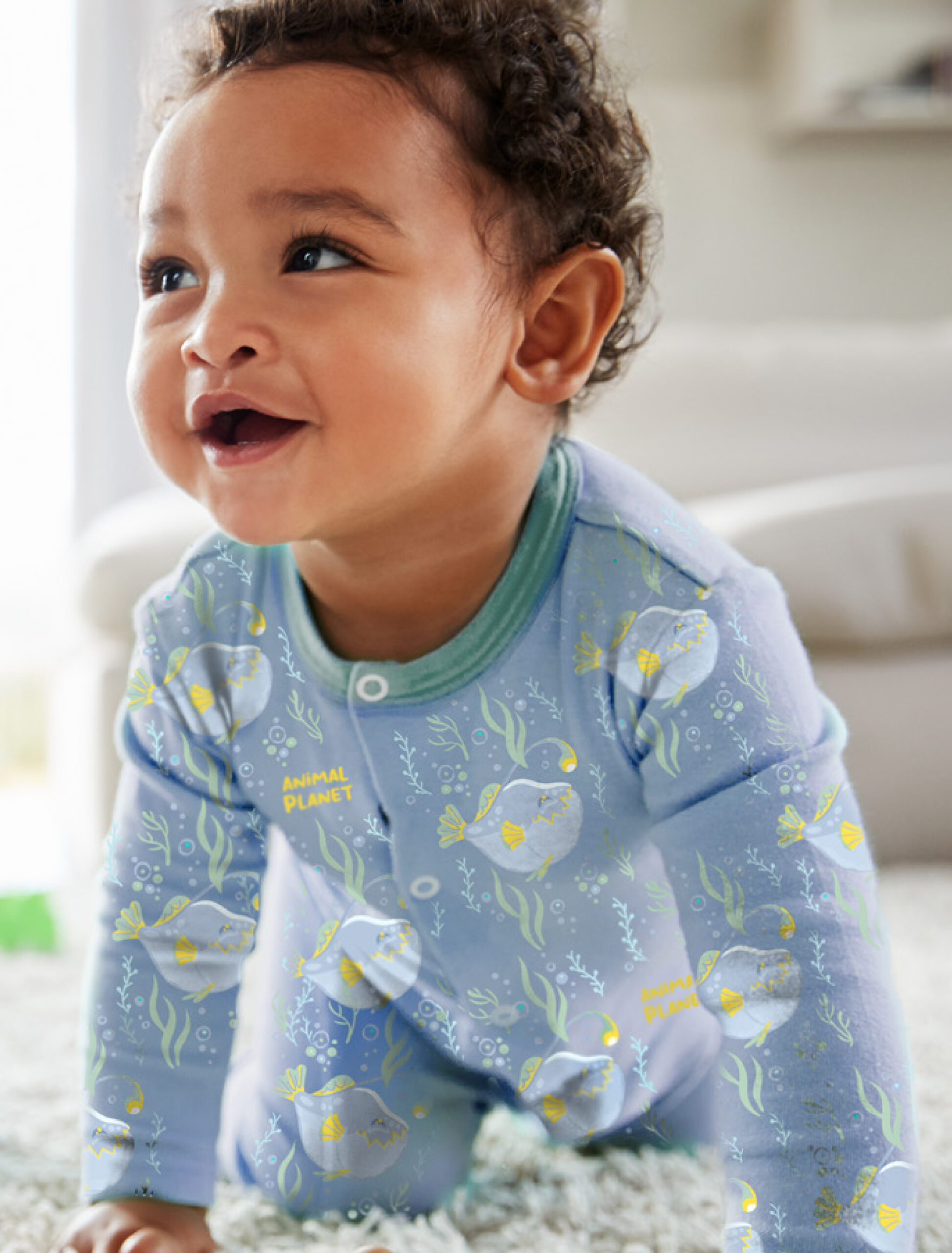 Smiling infant wearing pajamas featuring Under the Sea pattern.