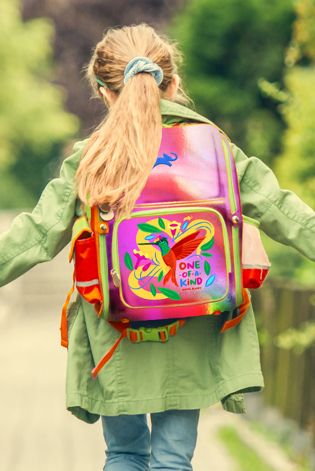 Girl wearing backpack featuring a colorful design with bird and the phrase "One-of-a-Kind."